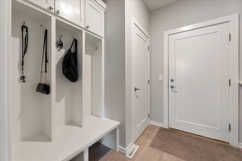 A hallway with a bench and a coat rack.