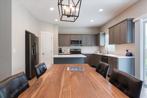 A modern kitchen with a wooden table and black leather chairs.