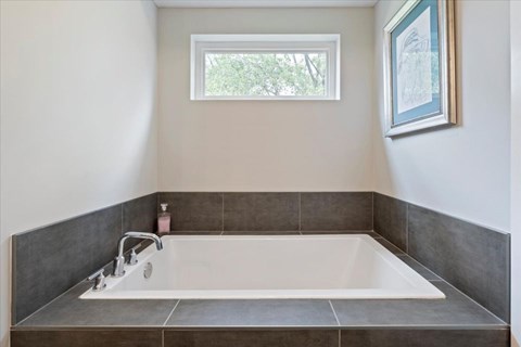 A bathroom with a tub and a window.