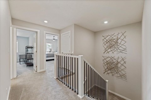A hallway with a staircase and a wall art.