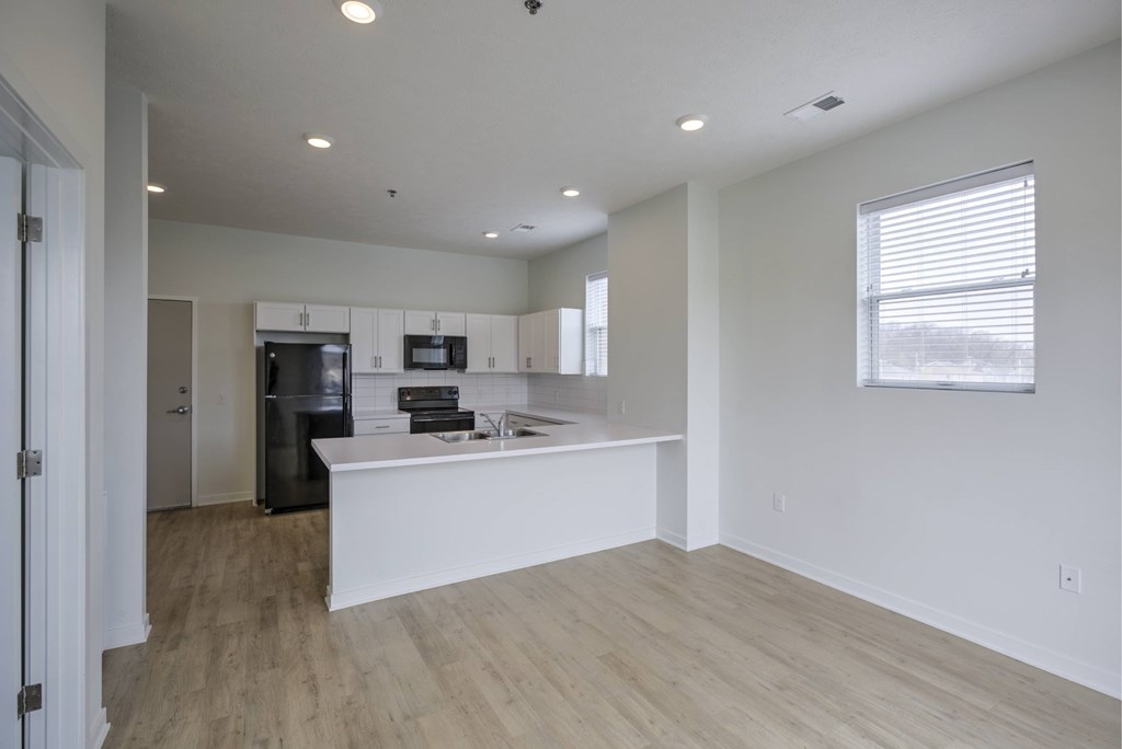 A kitchen with a white countertop and wooden flooring.