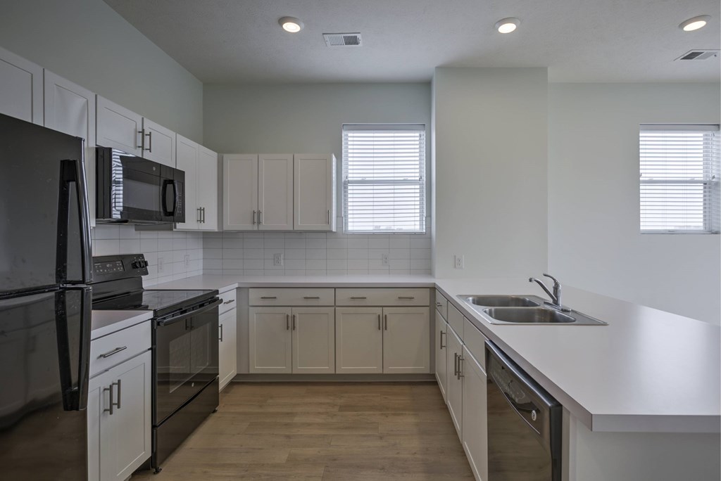 A kitchen with black appliances and white cabinets.