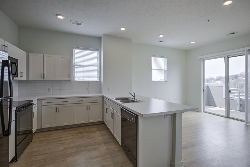 A kitchen with white cabinets and a black refrigerator.