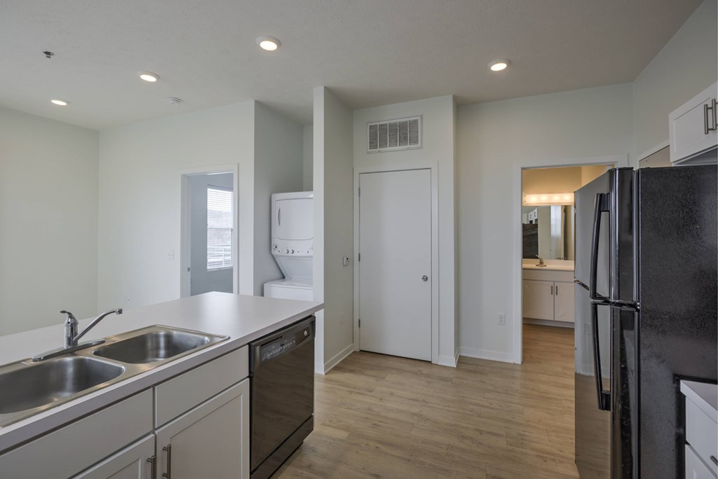 A kitchen with a black fridge and a white door.