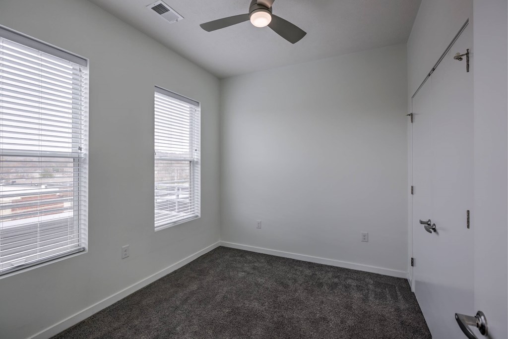 A room with a ceiling fan and carpeted floor.