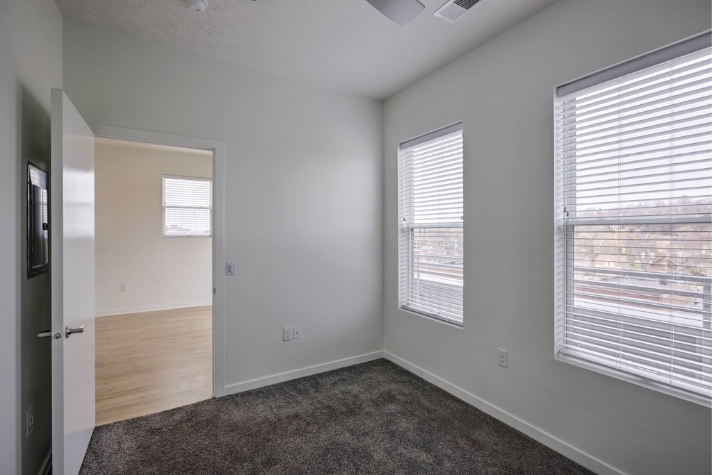 A room with a carpeted floor and a window with blinds.