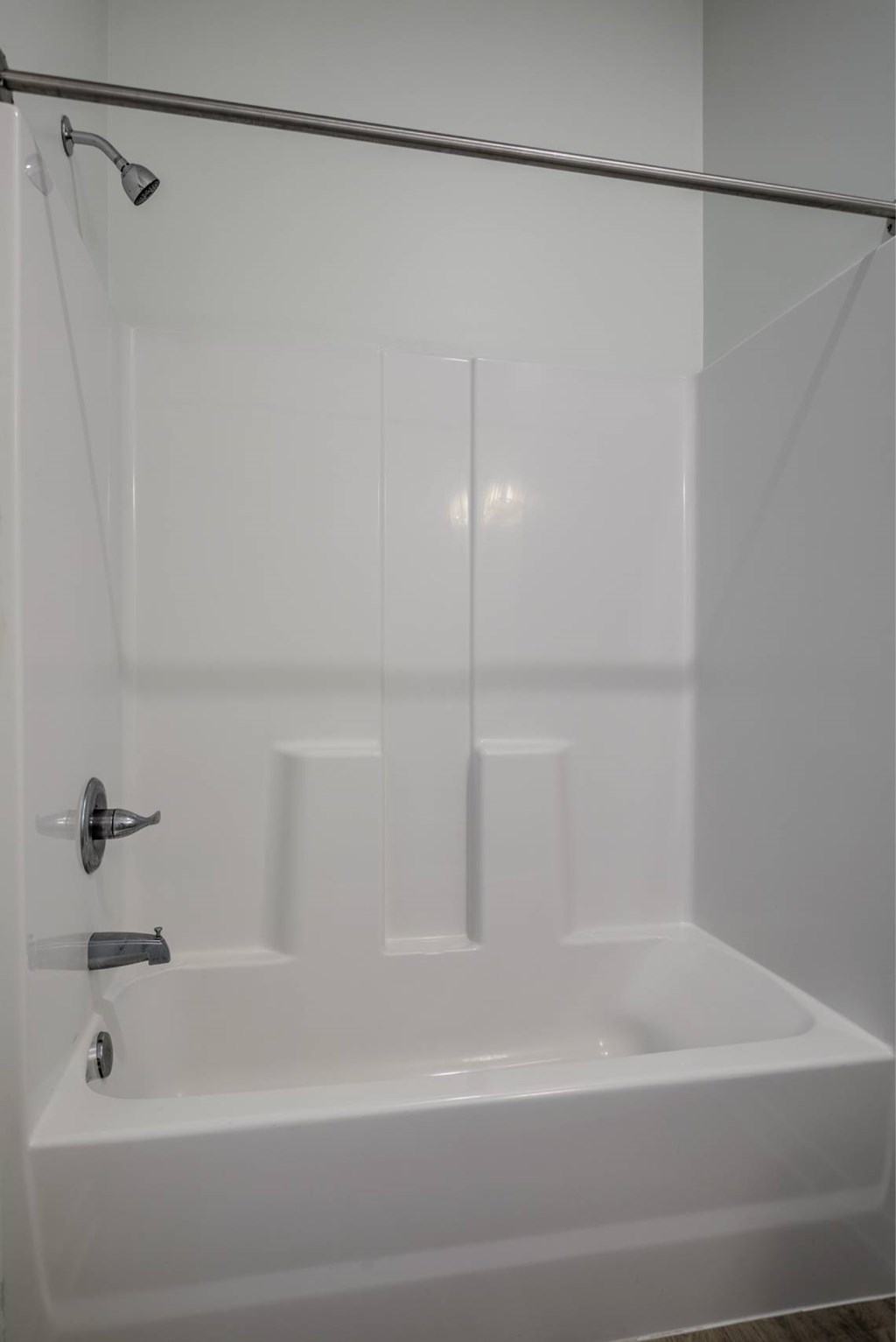 A white bathtub with a shower head and hand held shower.