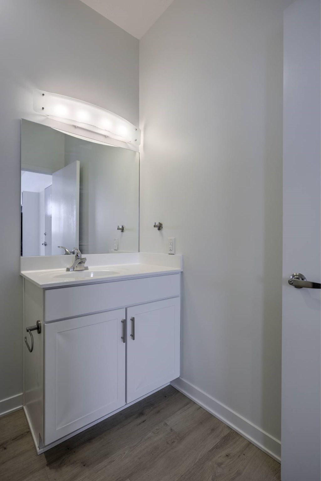 A white bathroom vanity with a mirror and lights above it.