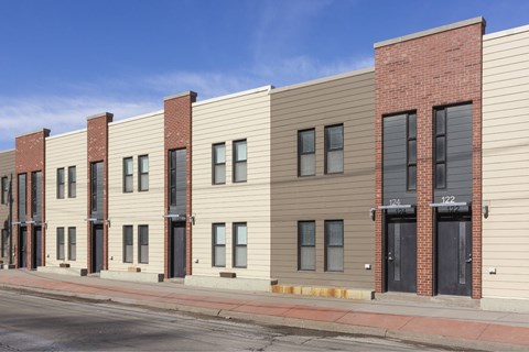 A row of modern buildings with a red brick building on the end.