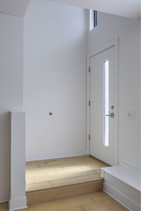 A white door is in a white room with a wooden floor.