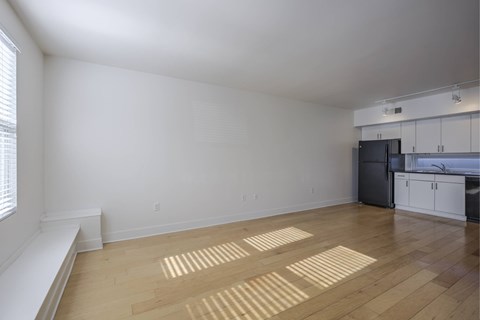 A room with wooden flooring and a window on the left side.