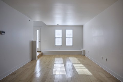 A room with wooden floors and two windows.