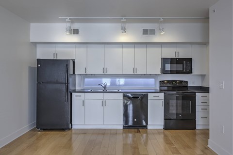 A kitchen with a black refrigerator, black oven, and black microwave.