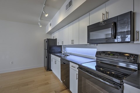 A modern kitchen with black appliances and wooden floors.