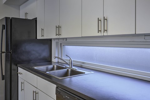A kitchen with a black refrigerator and a stainless steel sink.