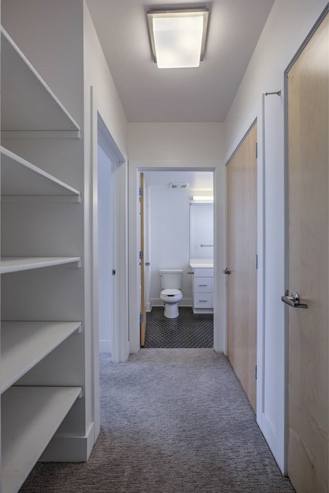 A hallway with a toilet in the distance and a door on the right.
