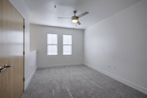 A room with a ceiling fan and carpeted floor.