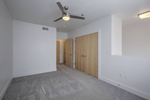 A room with a ceiling fan and carpeted floor.