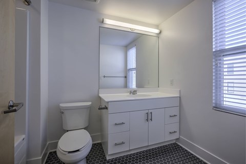 A white bathroom with a toilet, sink, and mirror.