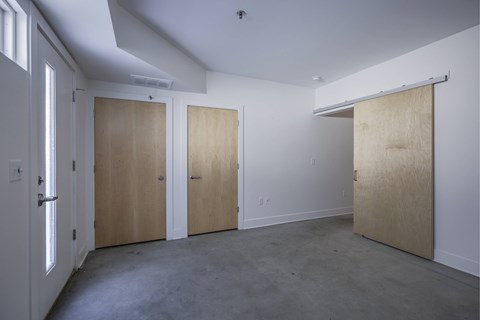 Three wooden doors are closed in a white room.