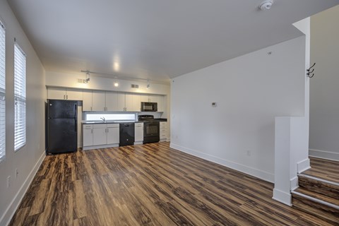 A kitchen with white cabinets and a black fridge.