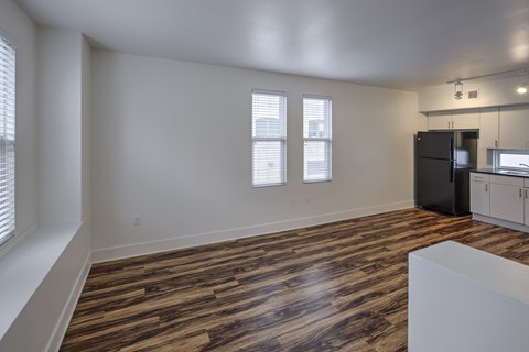 A room with wooden flooring and a black refrigerator.