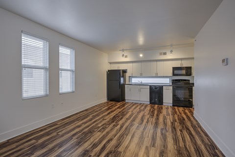 A kitchen with black appliances and wooden floors.