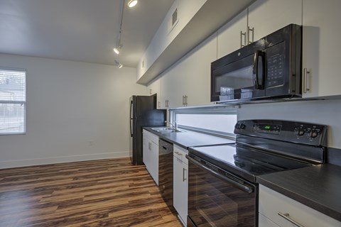A kitchen with black appliances and wooden floors.