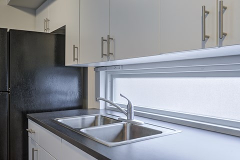 A modern kitchen with a black refrigerator and a stainless steel sink.