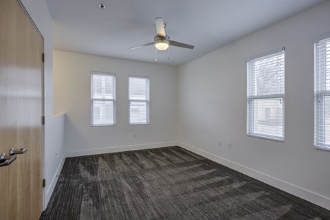 A room with a ceiling fan and carpeted floor.