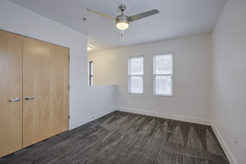 A room with a ceiling fan and a carpeted floor.