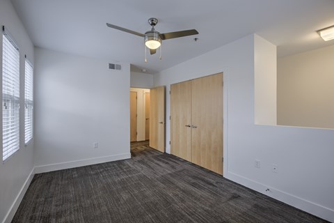 A room with a ceiling fan and a carpeted floor.