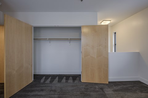 A room with a grey carpet and a white wall with a wooden door.