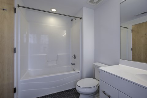 A white toilet sits next to a white bathtub in a bathroom.