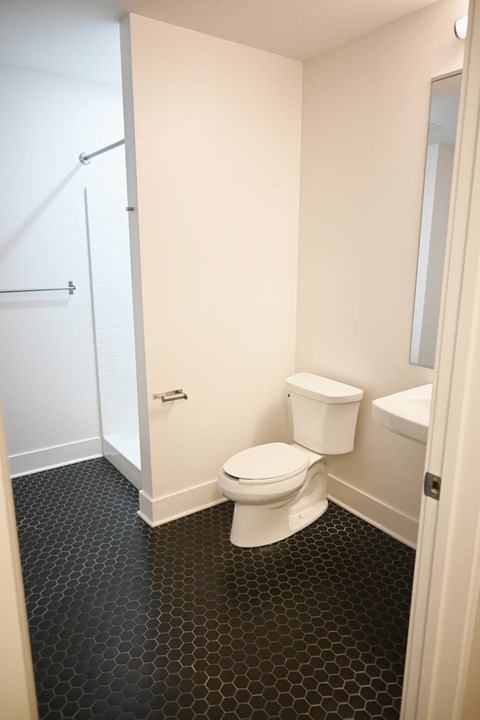 A white toilet in a bathroom with black hexagonal tiles.