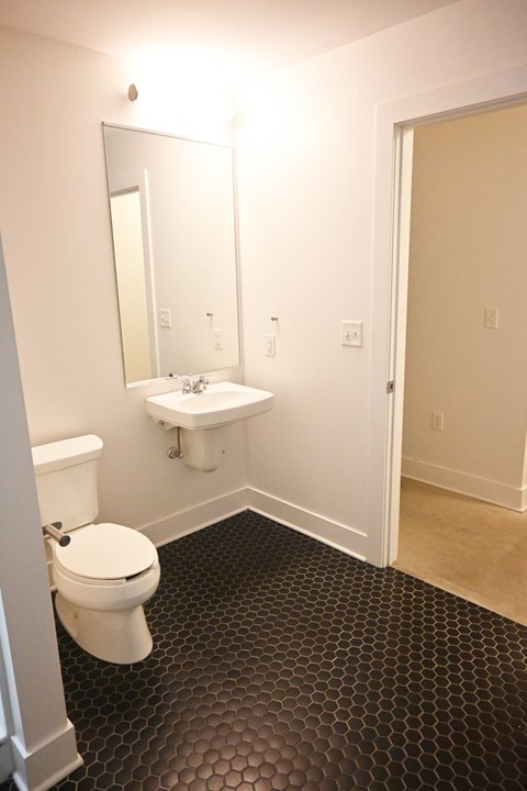 A bathroom with a toilet, sink and mirror.