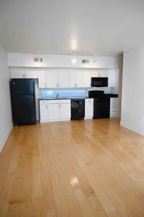 A kitchen with black appliances and wooden floors.
