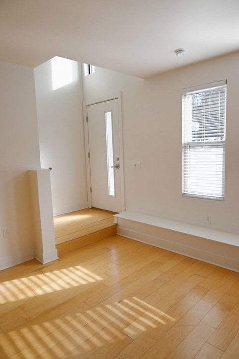A room with a wooden floor and a window with blinds.