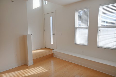 A room with a door, windows, and wooden flooring.