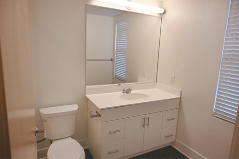 A white bathroom with a toilet, sink, and mirror.