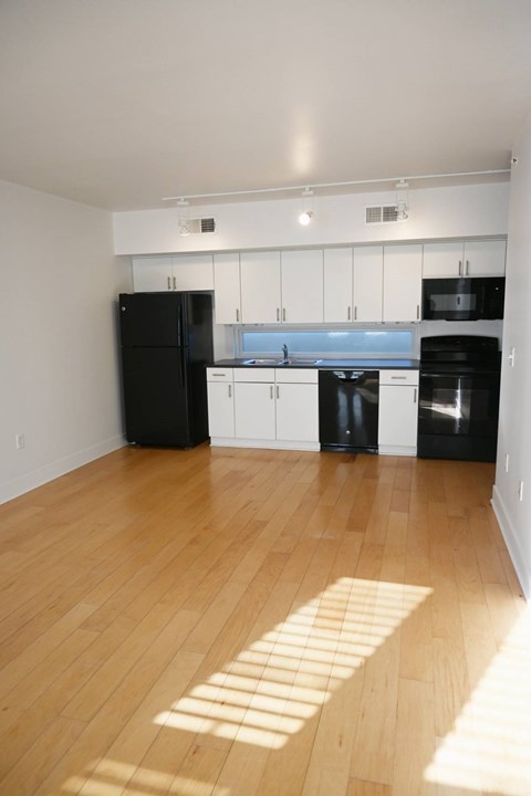 A kitchen with black appliances and wooden floors.