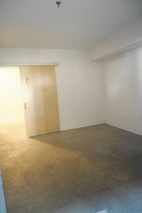 A room with a wooden door and a concrete floor.