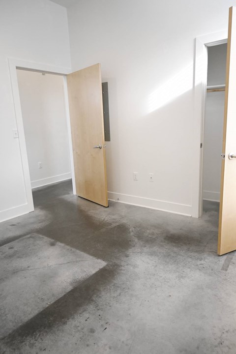 A room with two open doors and a concrete floor.
