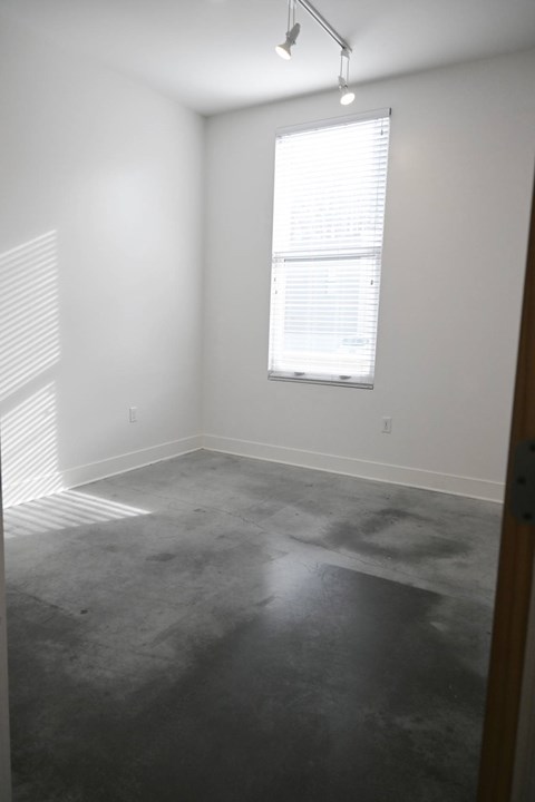 A room with a window and a concrete floor.