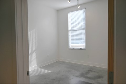 A room with a window and a grey floor.