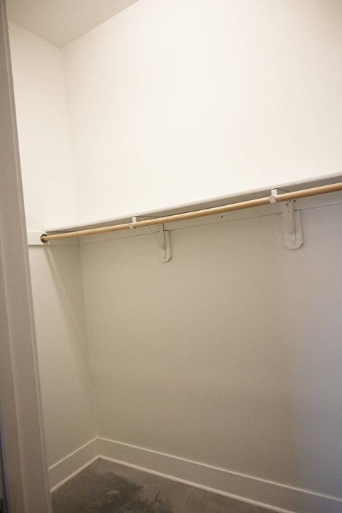 A white closet with a shelf and a white door.