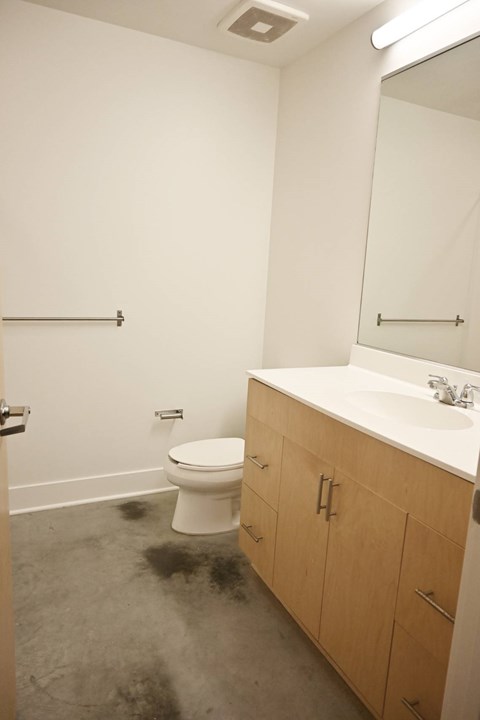 A bathroom with a toilet, sink, and mirror.