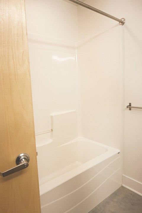 A white bathtub in a bathroom with a wooden door.