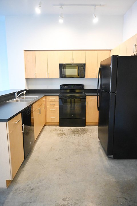 A kitchen with black appliances and wooden cabinets.