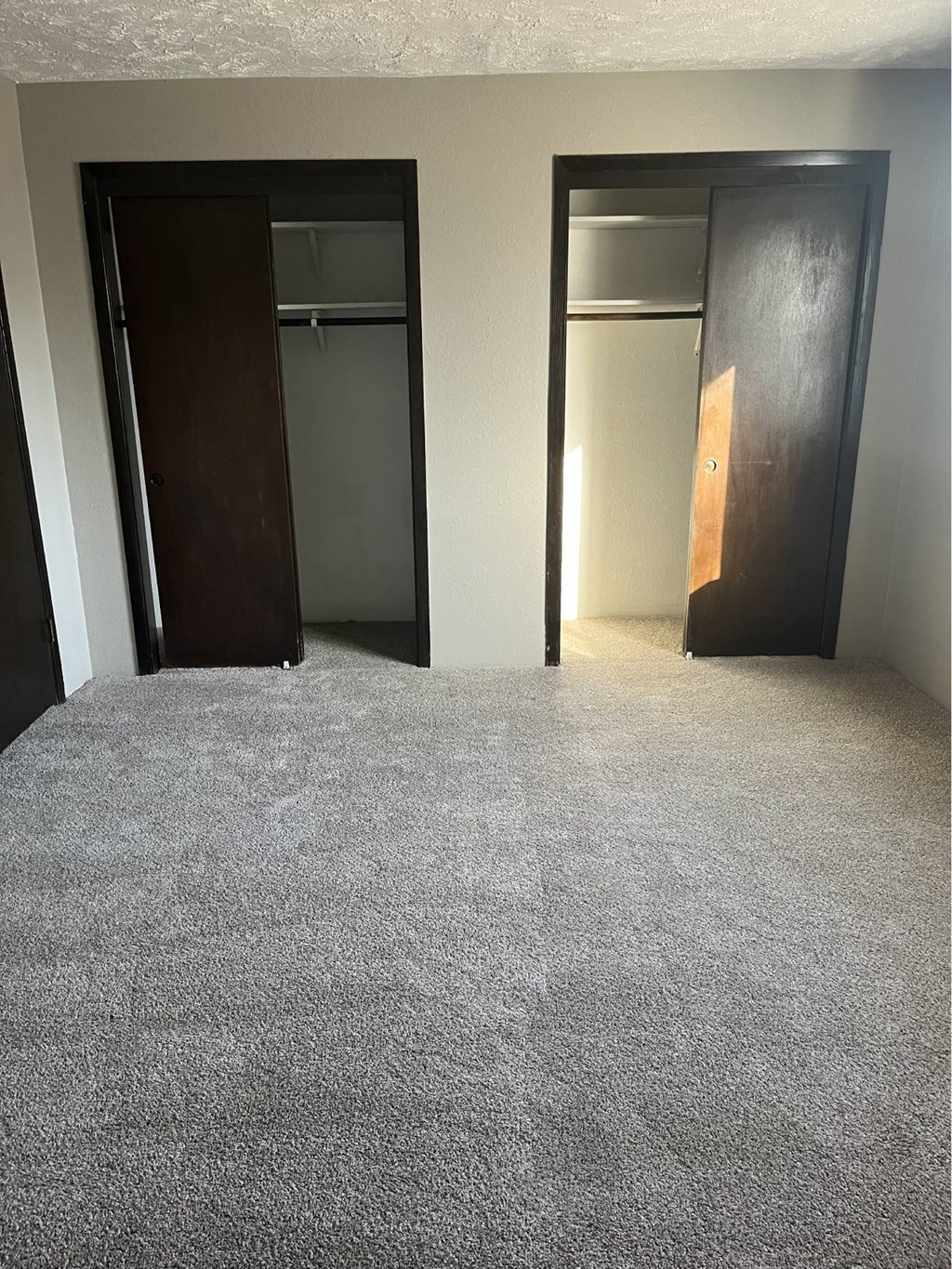 A carpeted room with two doors.